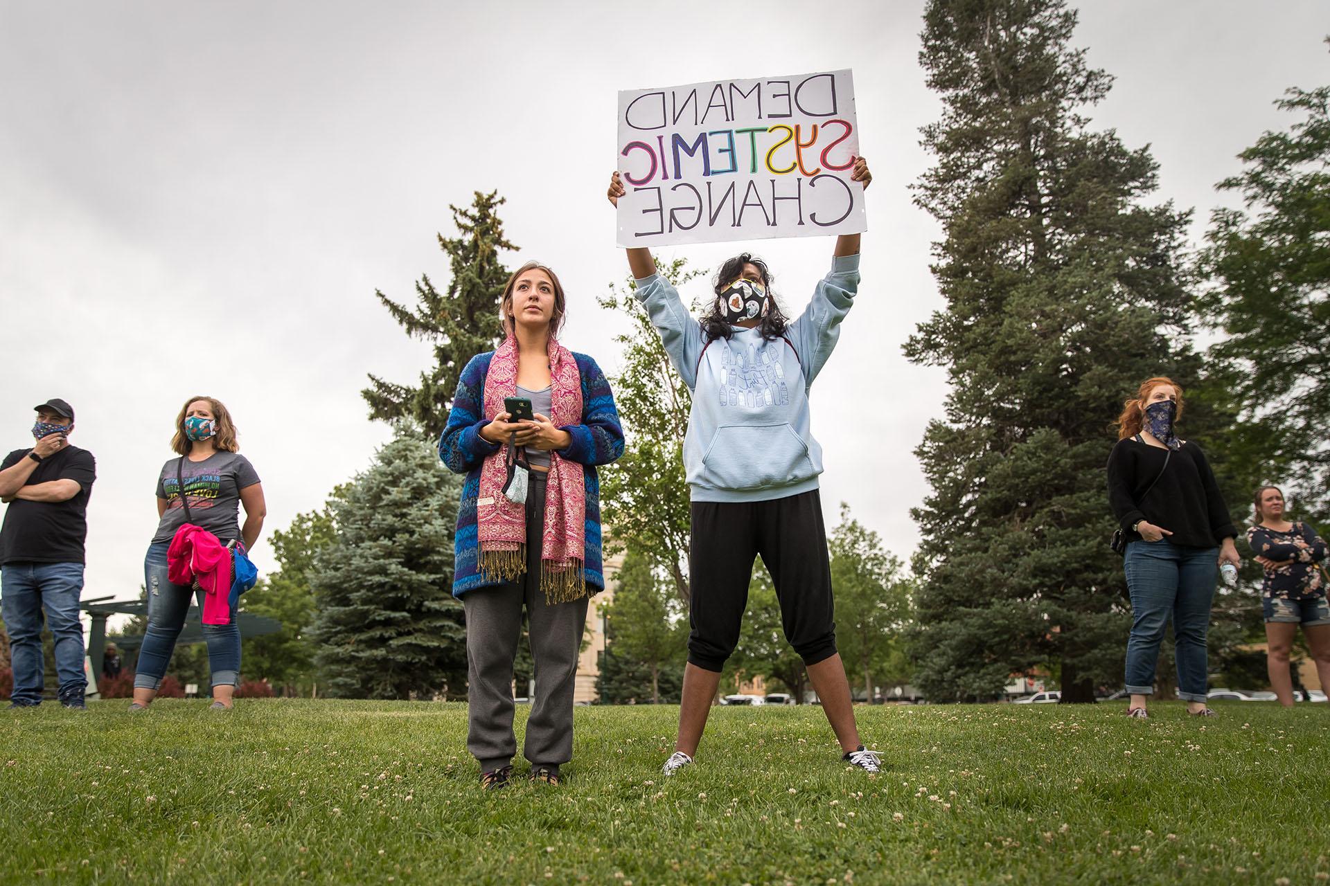 A women holds a sign reading 'Demand Systemic Change' at the Juneteenth march.