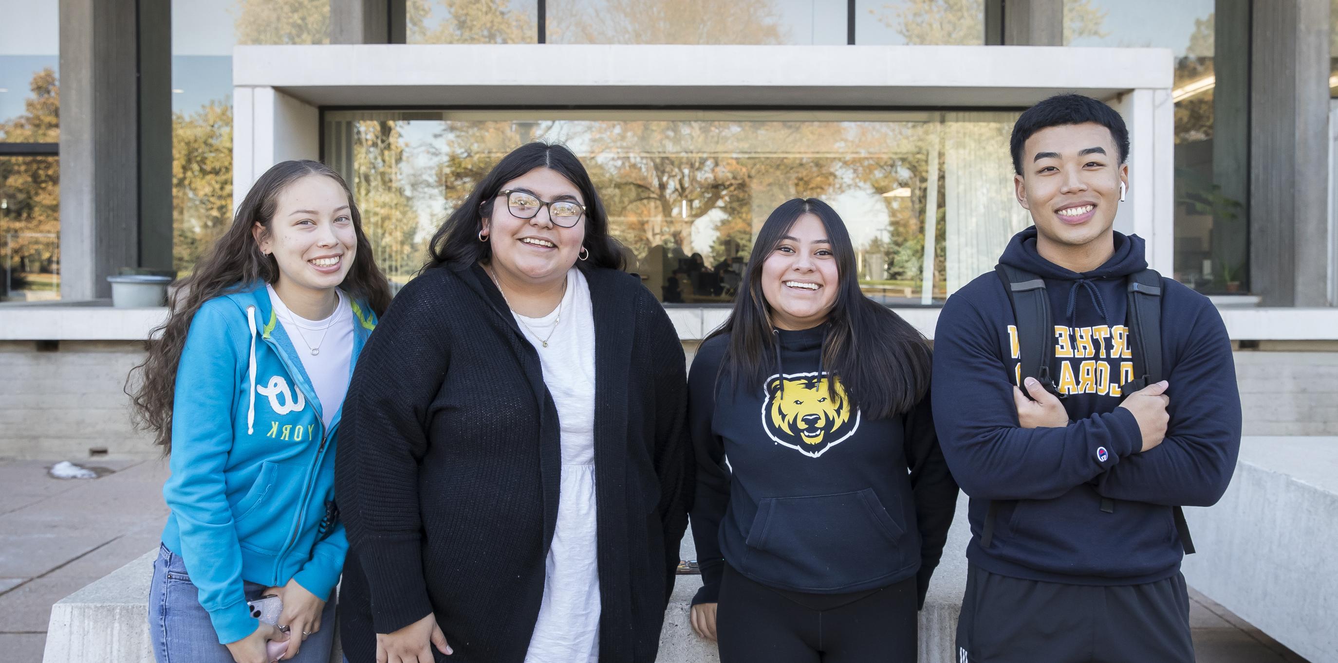 Four college students standing toge的r outside smiling