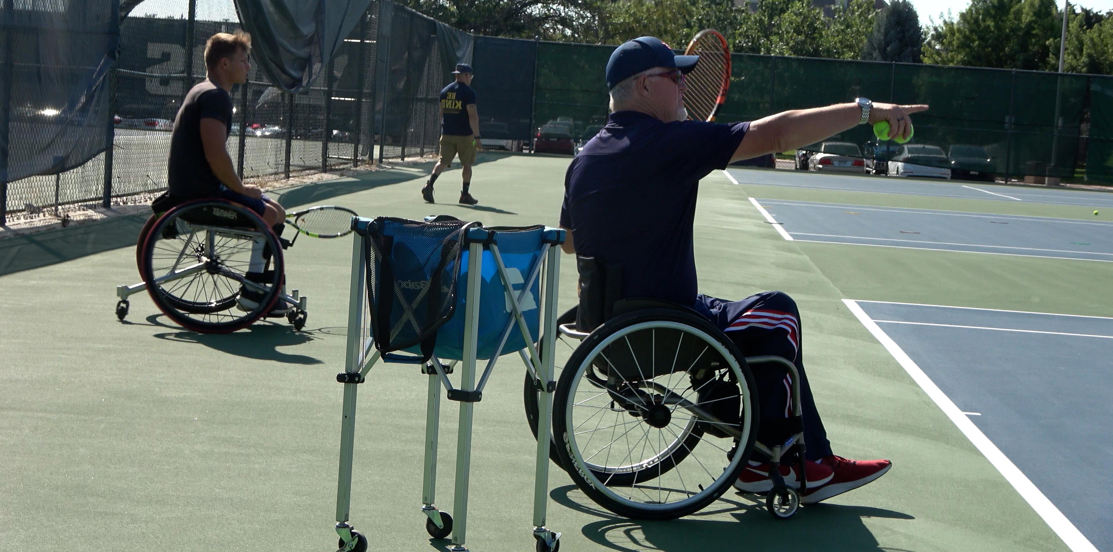 Scott Douglas coaching wheelchair tennis holding up his arm and pointing