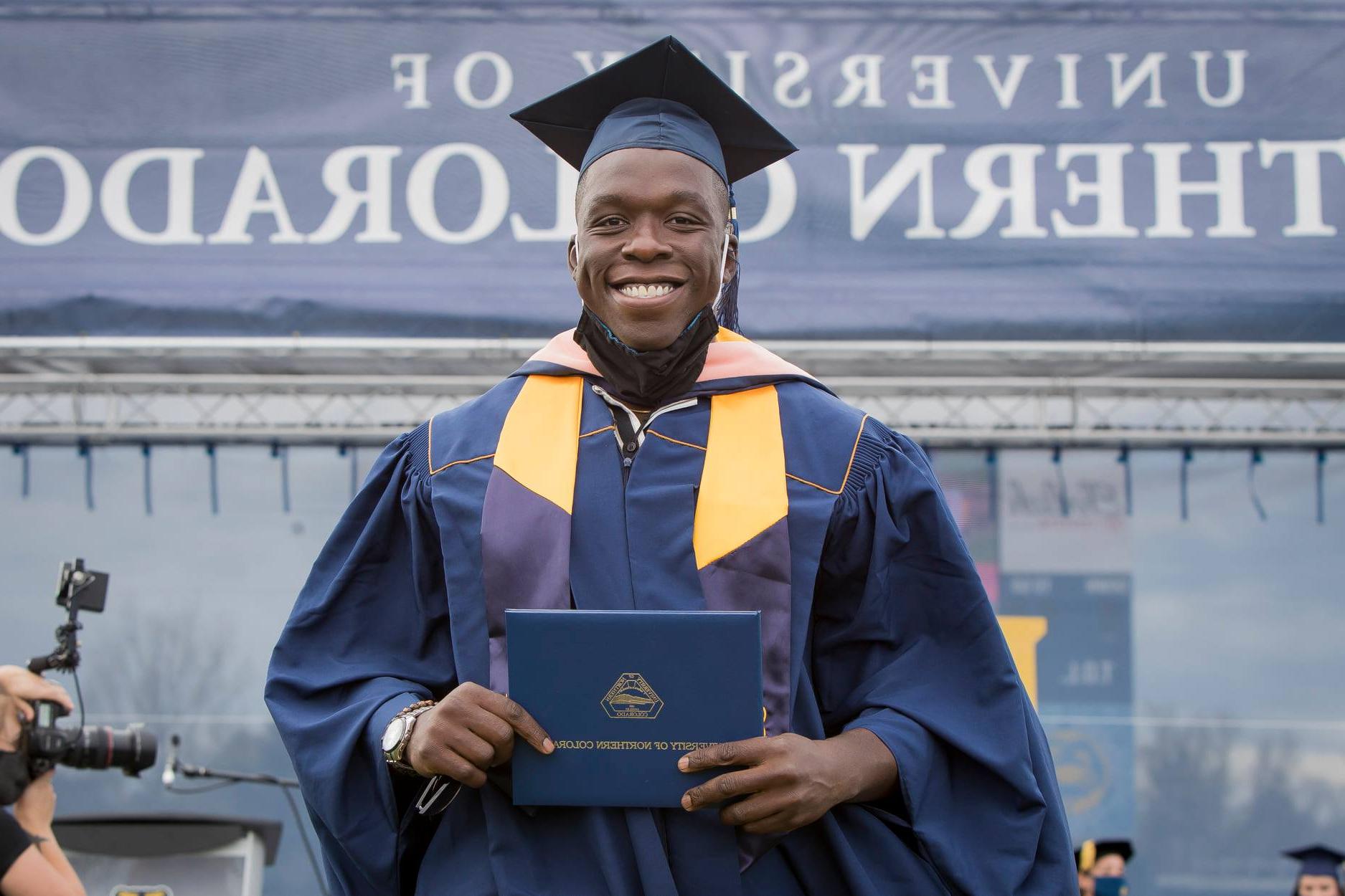 Colorado School of Public Health student Fisayo Awolaja accepting graduation certificate. Best Grad Schools 2023 US News logo in top left corner of image. 