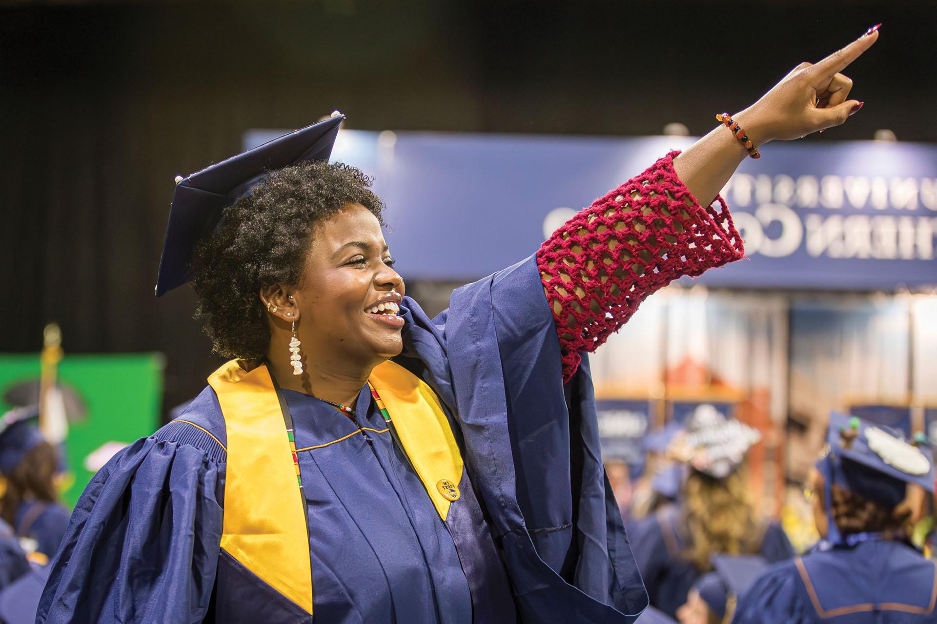 Undergraduate student points out into the ground at the 2024 UNC commencement ceremony.